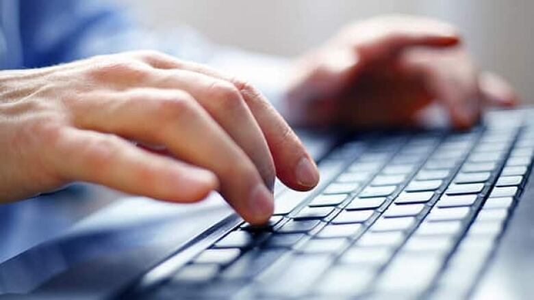 Hands type on a computer keyboard.