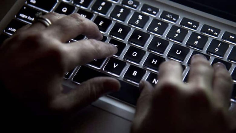 Hands type on a glowing laptop computer.