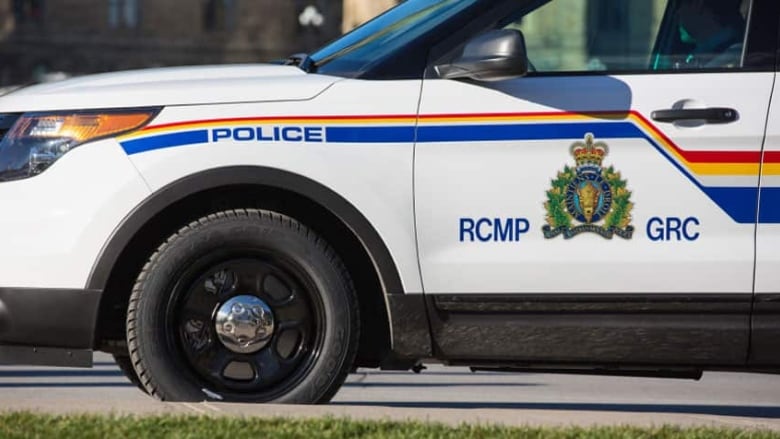 A white vehicle has a stripe of red, yellow and blue down the side, as well as a coat of arms, the letters RCMP and GRC, and the word police.