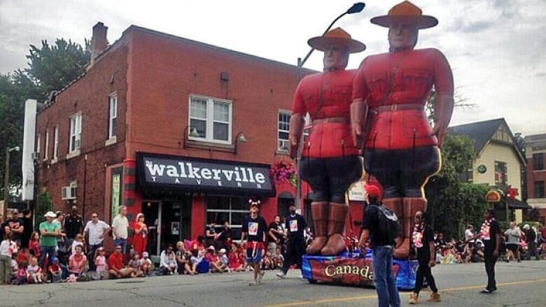 Giant inflatable RCMP balloons with crowds watching the Canada Day parade. 