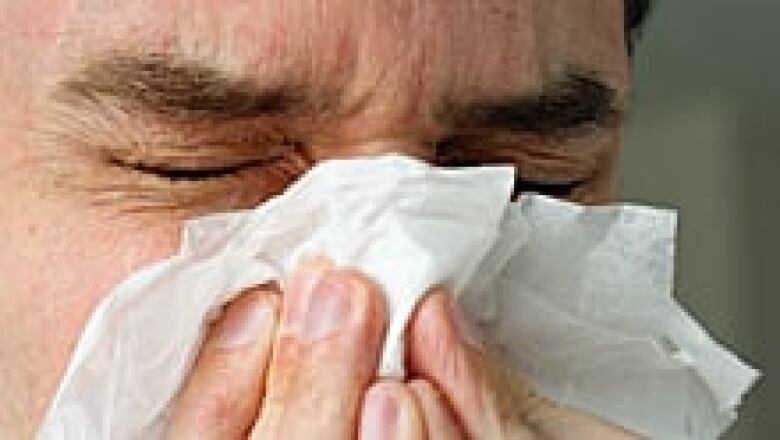 A close-up shot of a man sneezing into a tissue paper.