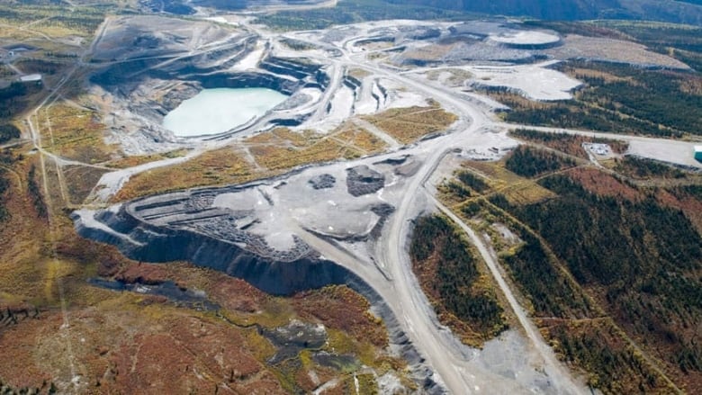 An aerial view of part of the abandoned Faro mine. In the foreground is a network of roads. Behind is a large open pit, which now houses the tailings.