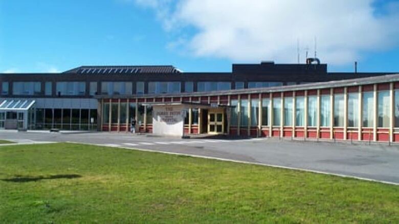 A long building with hospital sign in front.