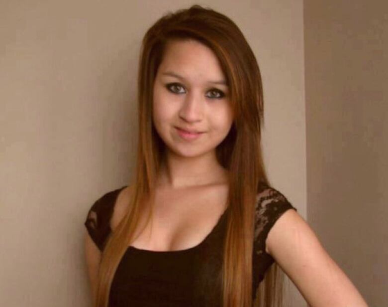 A young girl with straight hair past her shoulders is shown posing for a photo.