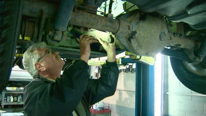 A man works on the underside of a vehicle