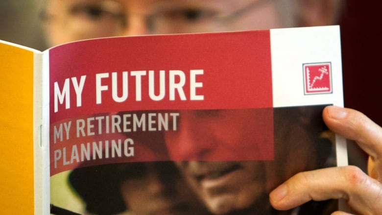 An older man holds a pamphlet with the words My Future My Retirement Plan.