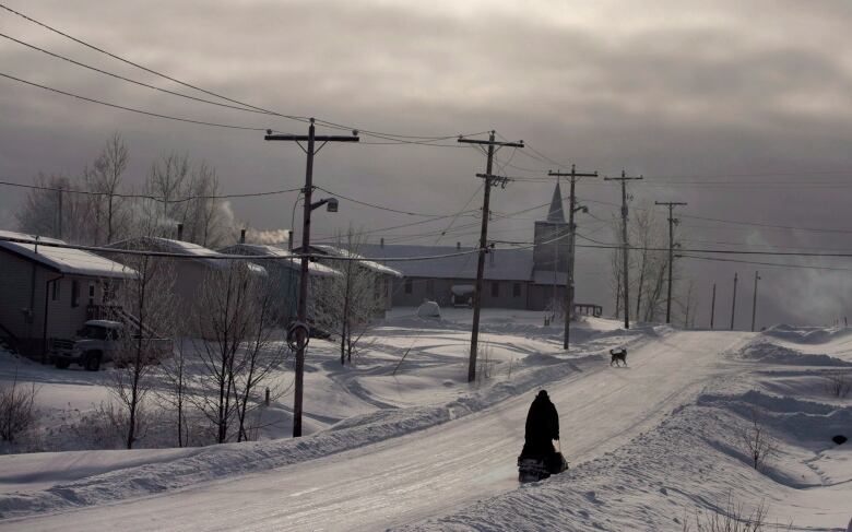 A snowmobile rides down the main street of Fort Hope First Nation in northern Ontario.