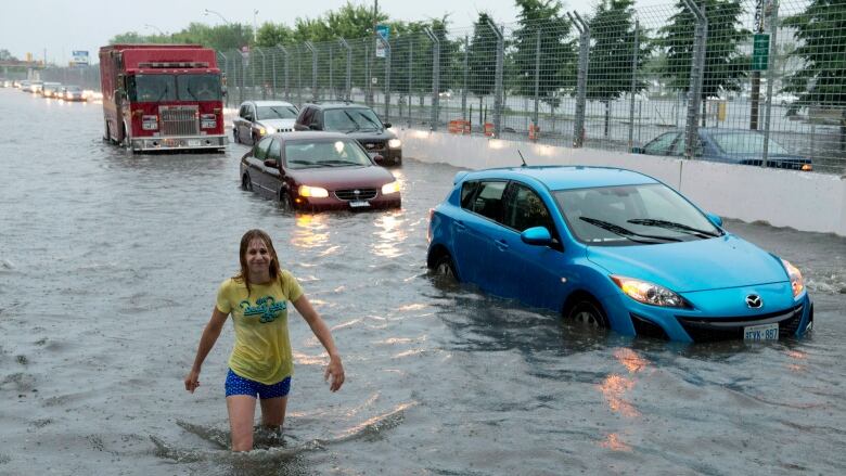 A woman wades through flood water on Lakeshore West during a storm in Toronto on Monday, July 8, 2013.