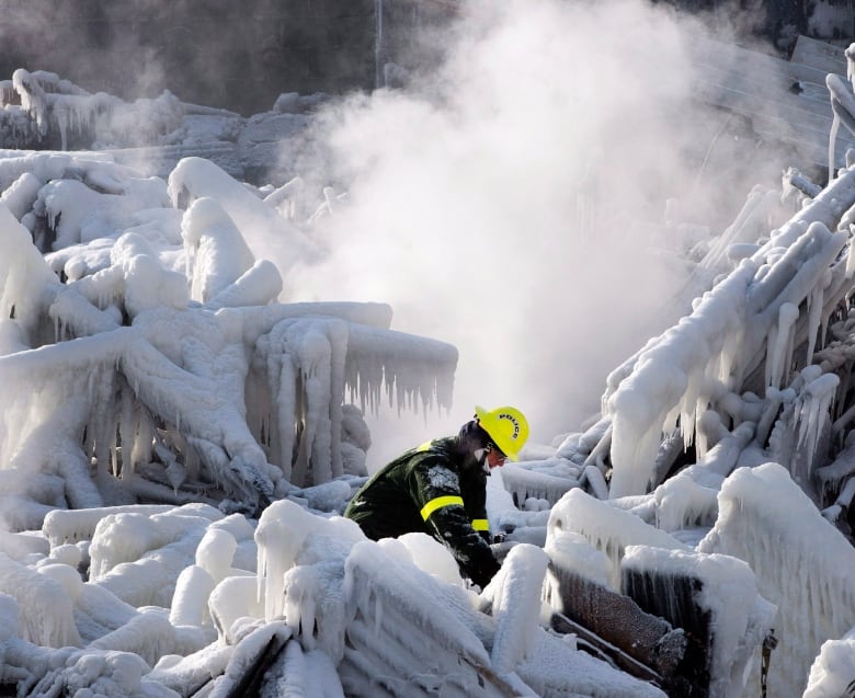 A fireman searches through the ruins of a building.