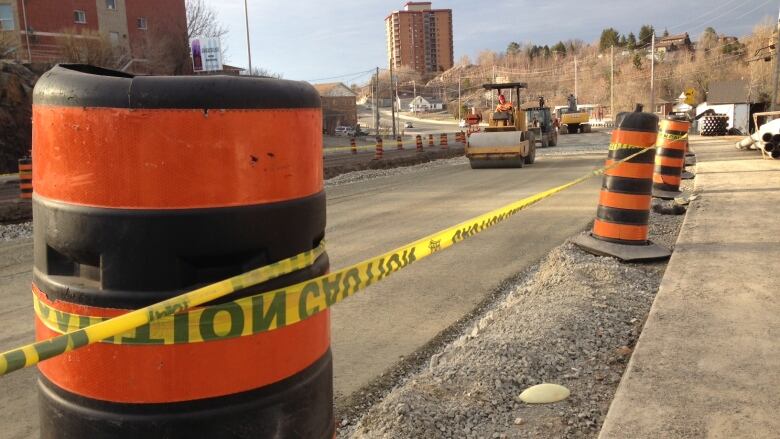 Several traffic cones line a street under construction.