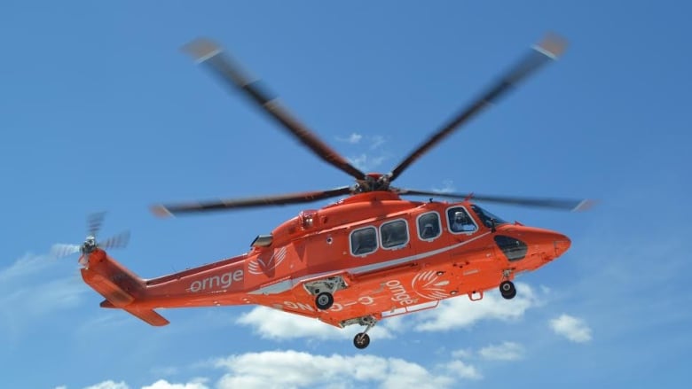 An ORNGE air ambulance is pictured against a blue sky in this stock photo.