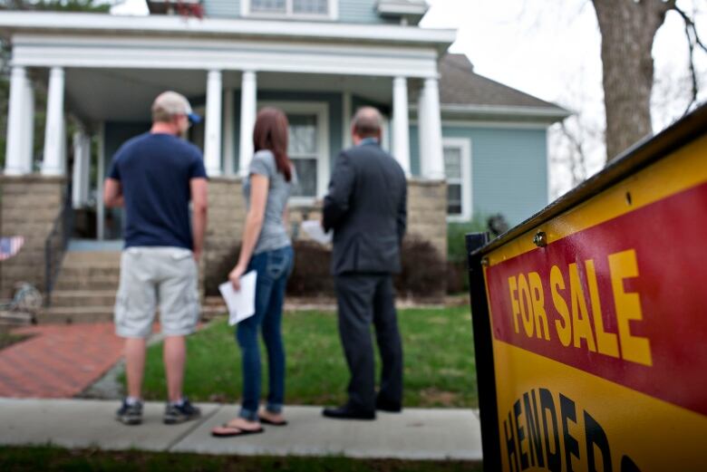 Three people look at a home for sale.