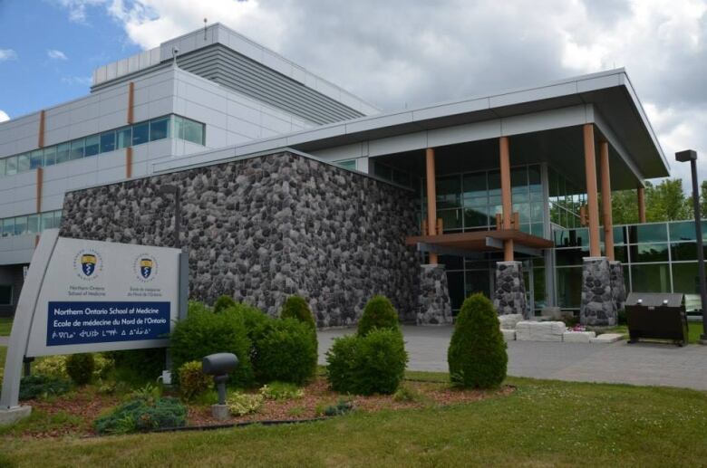 The entrance to NOSM university in Sudbury is a combination of glass windows, stone walls and wooden columns.