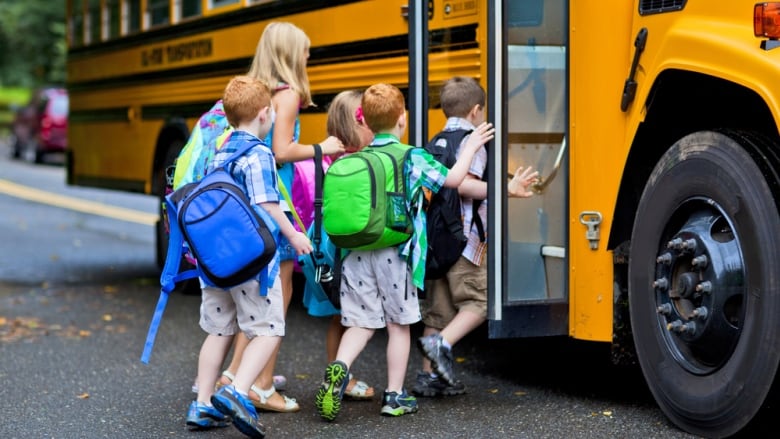 students line up to get on a yellow school bus.