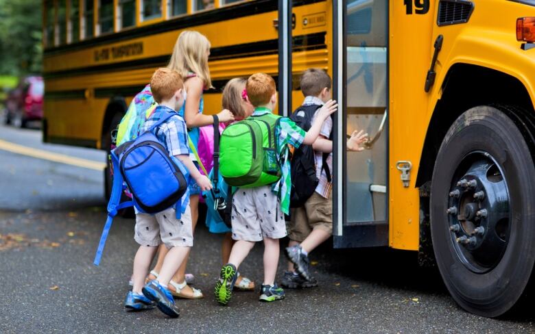 students line up to get on a yellow school bus.