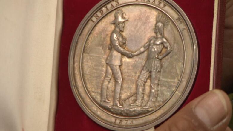 A picture of a treaty coin that has two people shaking hands