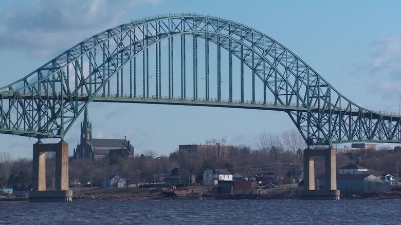 .A steel bridge sits across a river in an urban area.