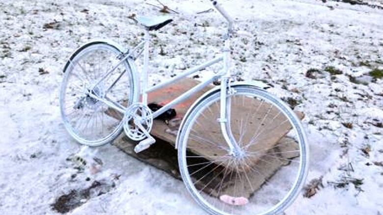 A bike painted white in the snow. 