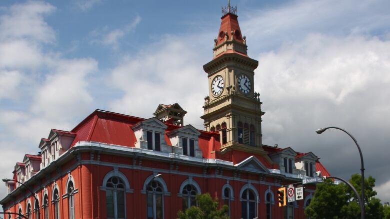 A red brick building on a street corner with a clock on a top spire.