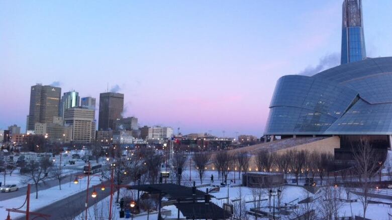 The Canadian Museum for Human Rights can be seen in the foreground, with the Winnipeg skyline behind it, in winter.