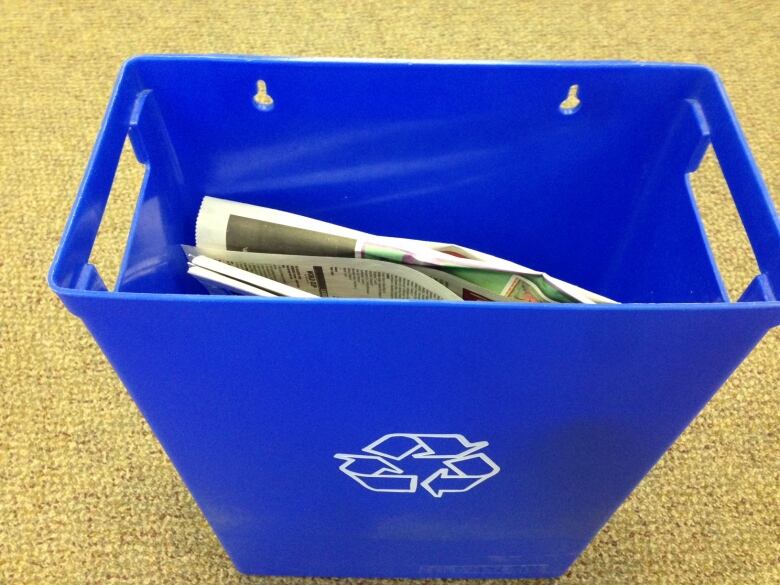 A small recycling bin with newspapers in it