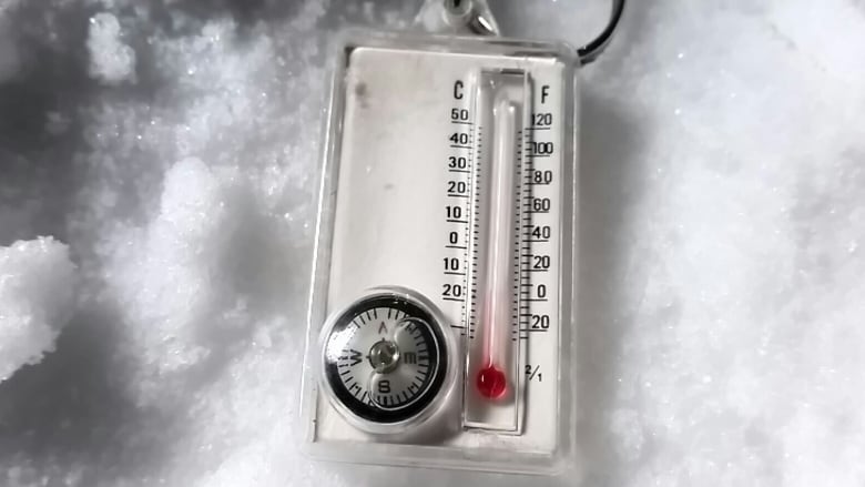 a thermometer is pictured in the snow.