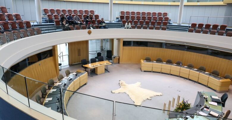 A building with a gallery and seats and tables below.