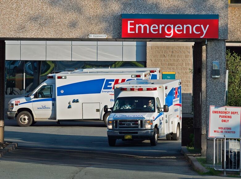 Two ambulances wait outside a hospital emergency department.