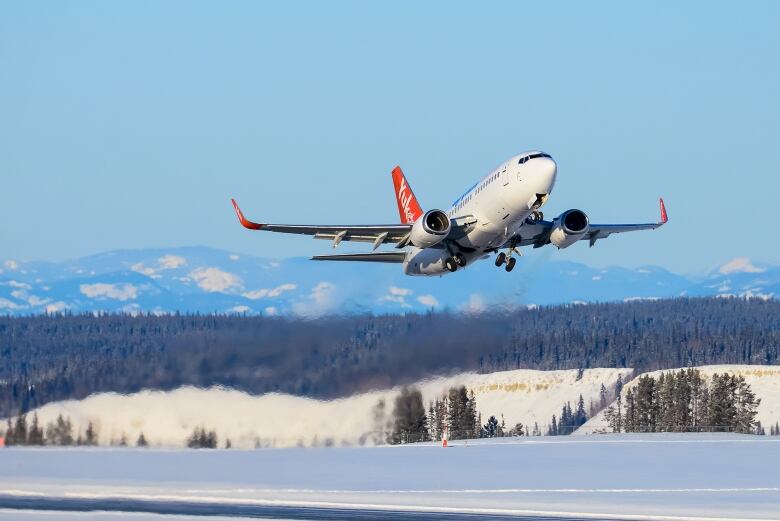 A plane takes off with mountains in the background. 