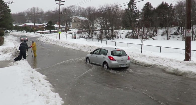 Some residents try to unplug a clogged drain on McLennan Avenue in Halifax in February 2015.