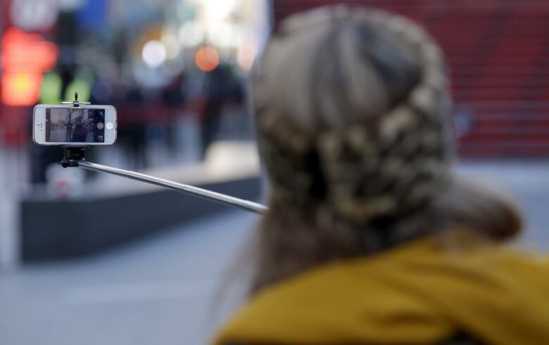 The back of a person holding a phone on a selfie stick.