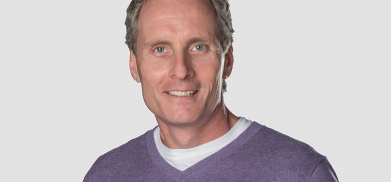 Man with purple sweater smiles to camera