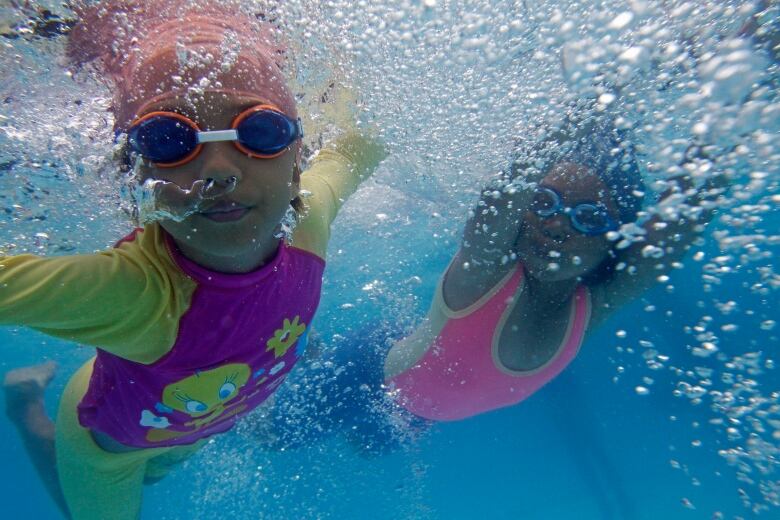 Two little girls swimming underwater at a pool