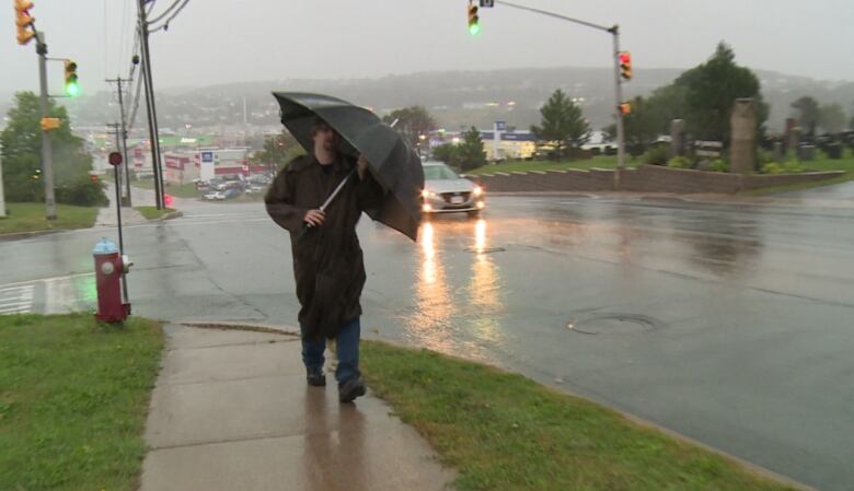 Man walking on a sidewalk on a rainy day.