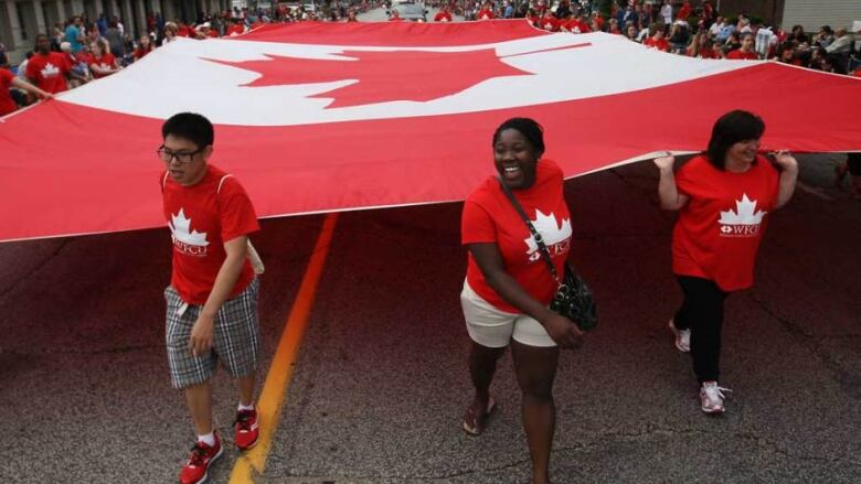 A group carries a giant Canada flag.