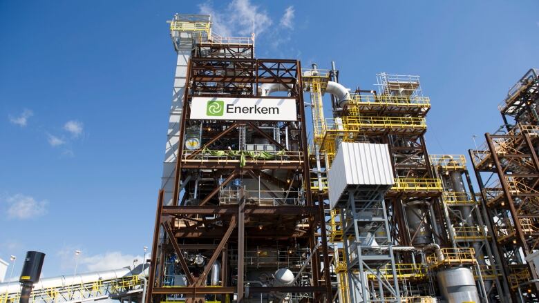 An industrial facility outdoors under a blue skies, showing pipes, walkways and stairways.