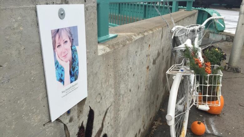 A photo of a woman and a white-painted bicycle adorn a concrete wall.