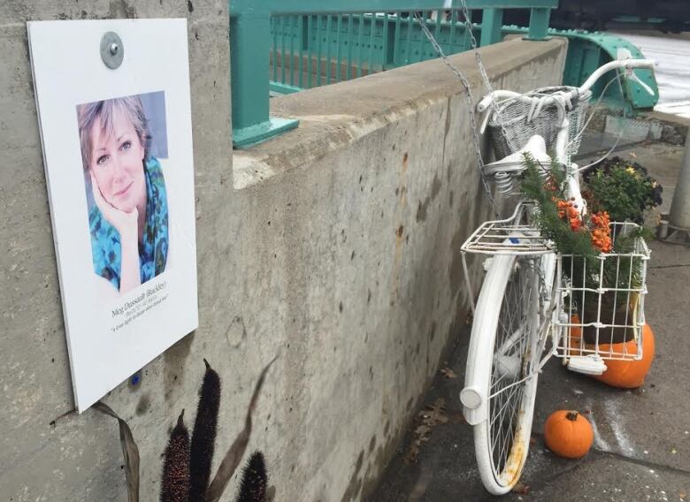 A photo of a woman and a white-painted bicycle adorn a concrete wall.