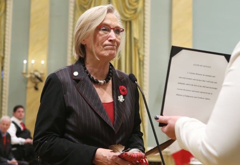 A woman speaks into a microphone and take an oath of office.