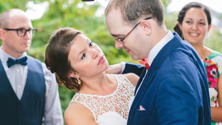 A woman in a wedding dress is dancing with a man in a blue suit. 