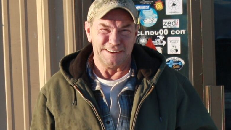 A man in a cap stands outside a building.