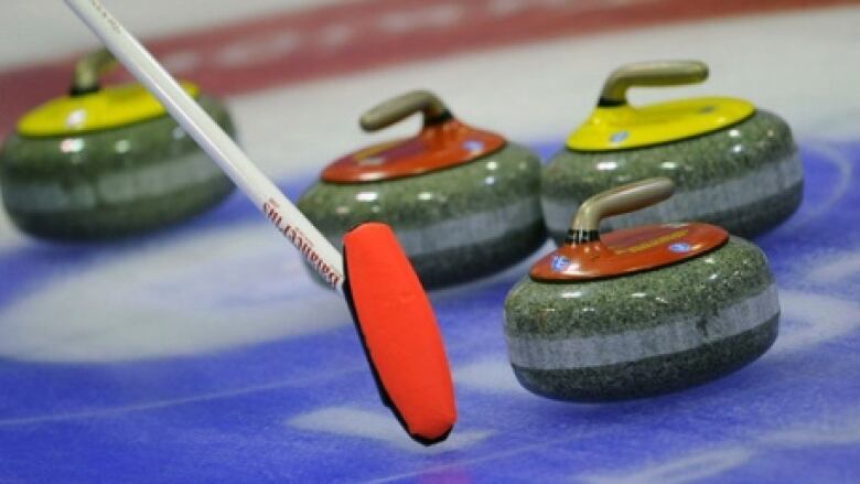 A curling puck is next to a curling brush