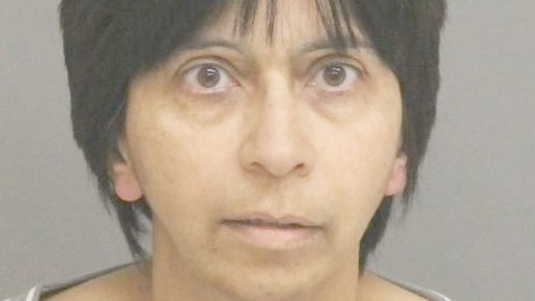 A woman with short dark hair appears unsmiling in a mugshot. 