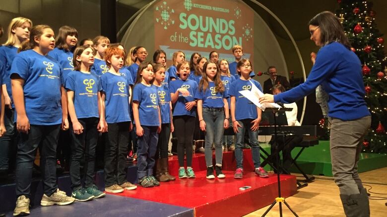 A children's choir in blue tshirts perform for the crowd