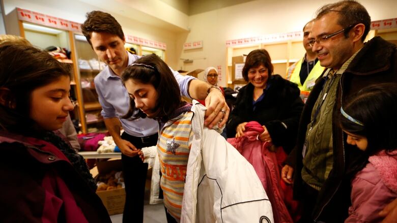 Politicians help new arrivals put on winter coats.