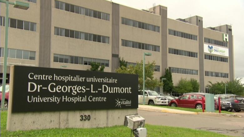 A hospital building with a sign in front that says 