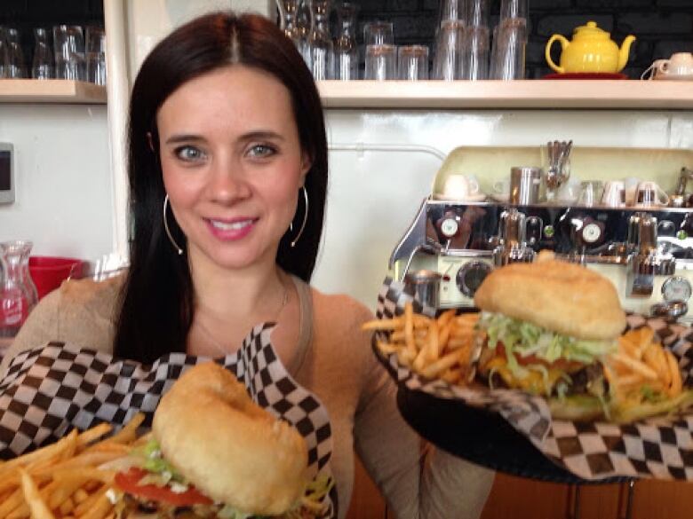 A woman holds burgers. 