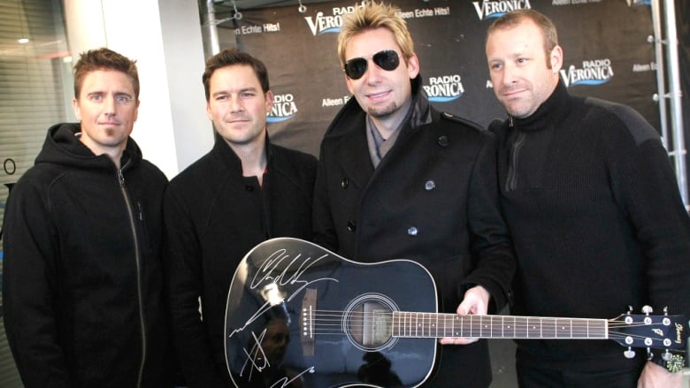 Members of Canadian rock band Nickelback pose with a signed guitar in the Netherlands in November 2013. While their music has gone international, many of the band members are from a small town in Alberta that proudly stands behind them.