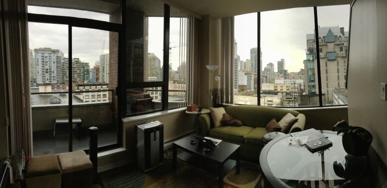 A room with ceiling-to-floor windows overlooks the Vancouver skyline.