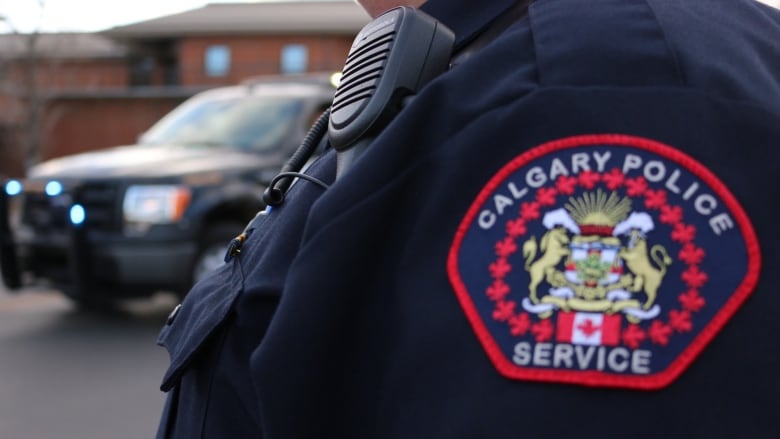 The official emblem of the Calgary Police Service can be seen on the uniformed shoulder of a police officer.